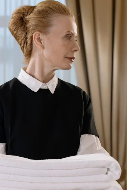 A woman vacuuming a couch in a cozy living room setting, emphasizing daily housework.